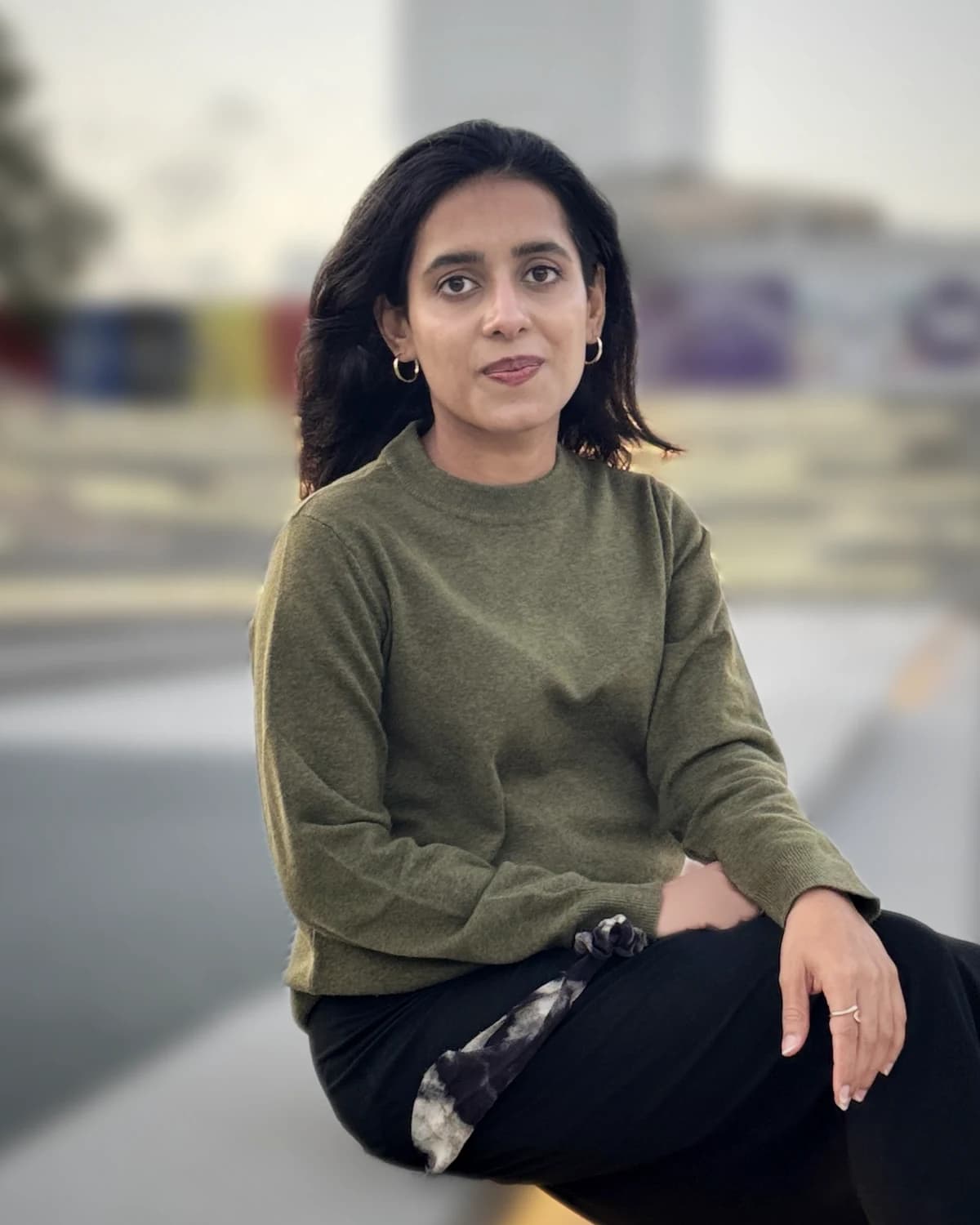 Nimra Zahid seated on stone steps in a modern city square